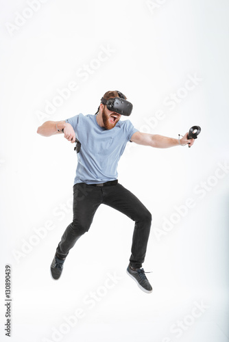 Happy bearded man wearing virtual reality device while jumping