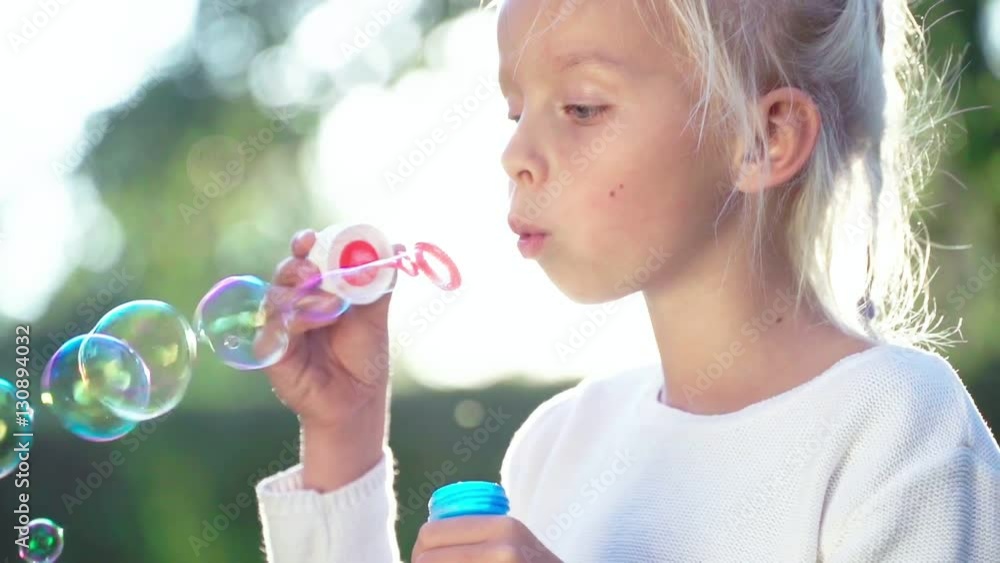 Little girl blowing soap bubbles outdoors Little girl blowing soap bubbles outdoors