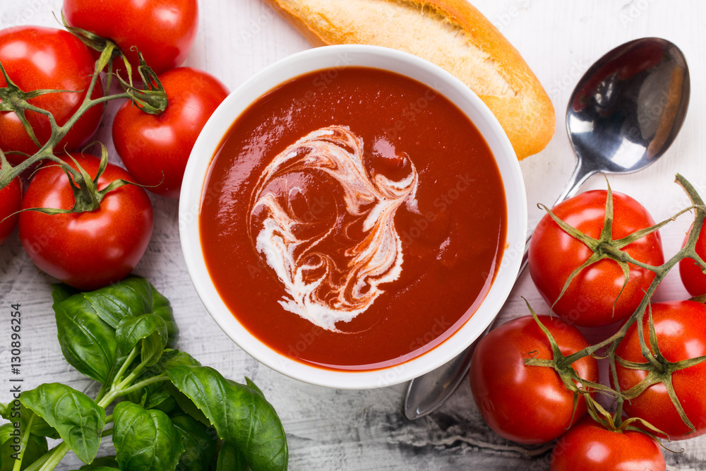 Tomato soup with basilic, cherry tomatoes and baguette on white background Top view Tomato soup with basilic, cherry tomatoes and baguette on white background Top view
