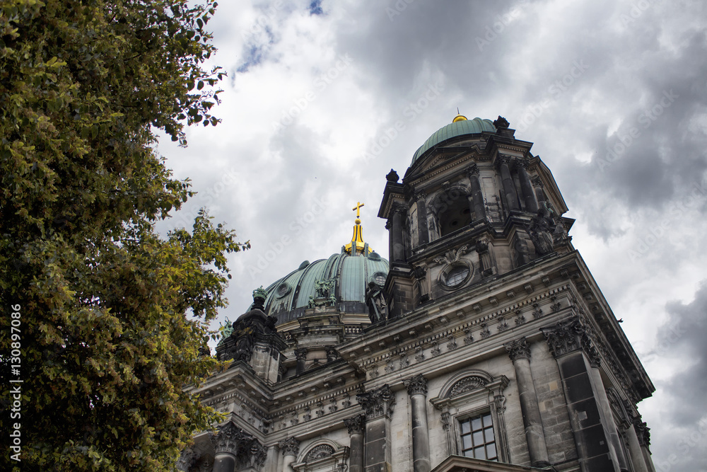 Bottom view of Berliner Dom with cloudy sky in the background in Berlin. Majestic 1800s cathedral with an organ with 7,000 pipes, plus royal tombs & a dome for city views.