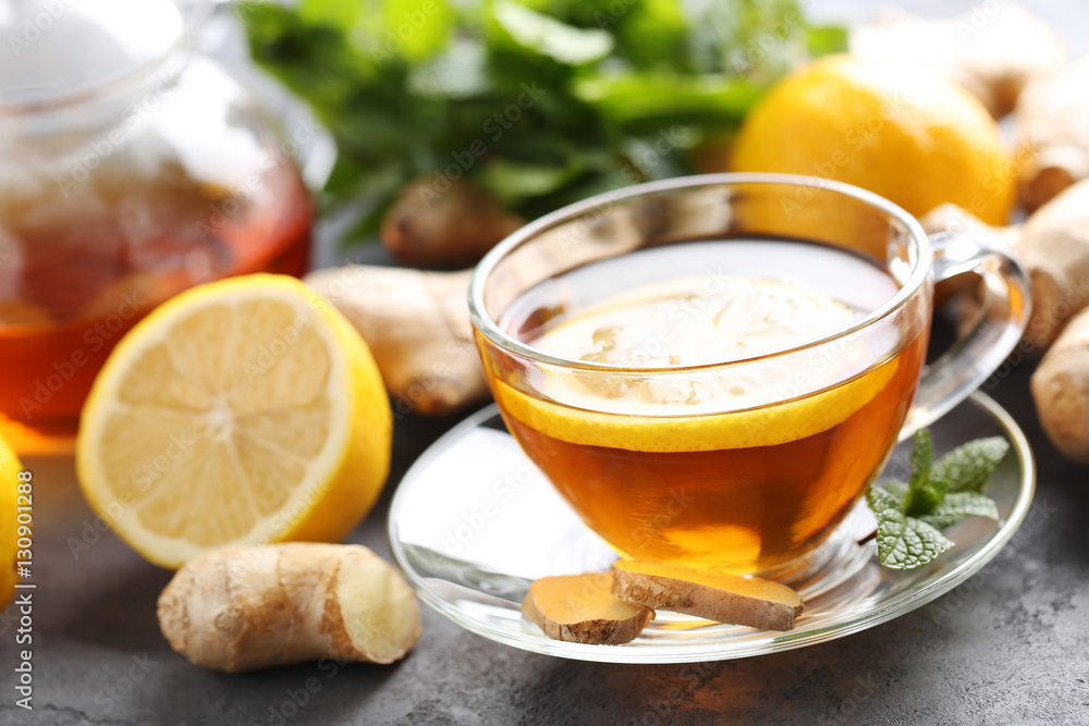 Cup of tea with ginger root and lemon on grey wooden table Cup of tea with ginger root and lemon on grey wooden table