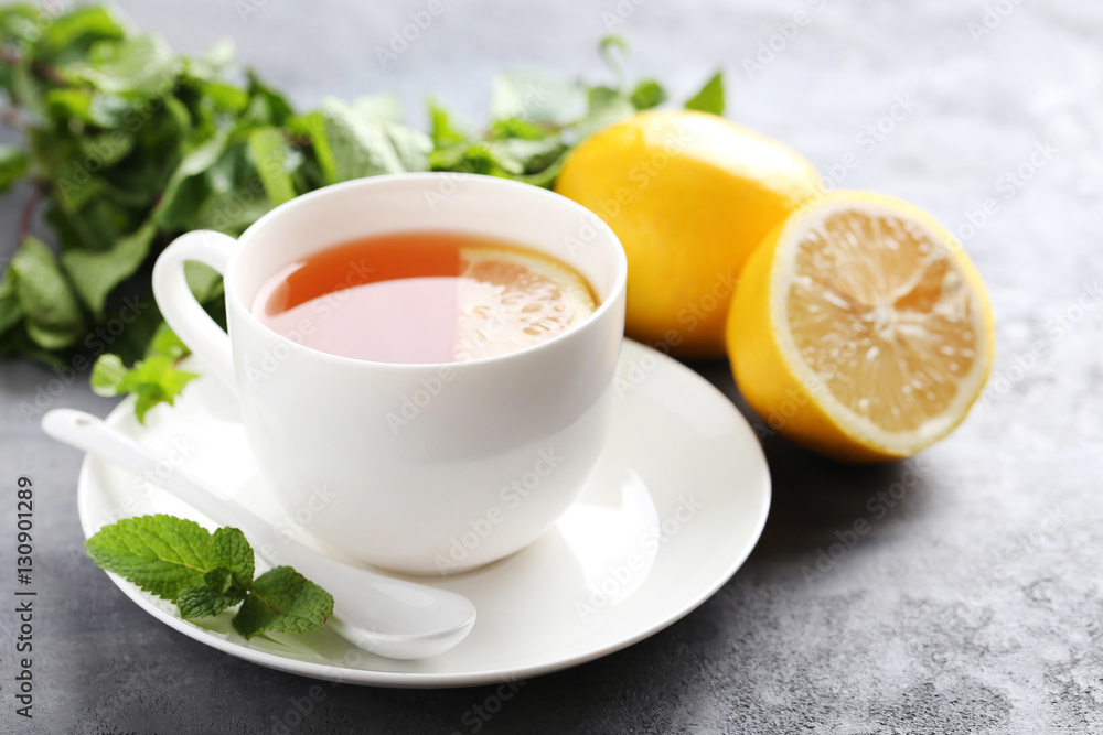 Cup of tea with mint and lemon on grey wooden table Cup of tea with mint and lemon on grey wooden table