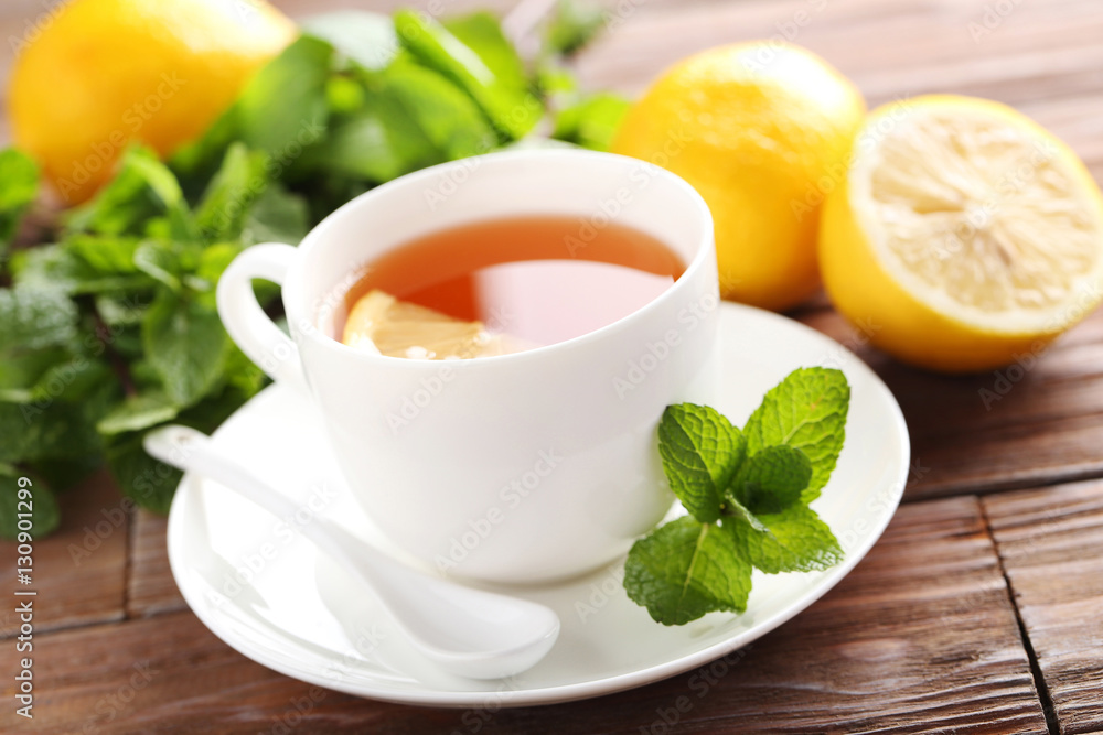 Cup of tea with mint and lemon on brown wooden table Cup of tea with mint and lemon on brown wooden table