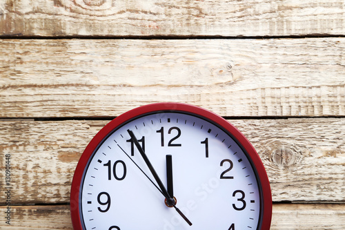 Red round clock on a grey wooden table
