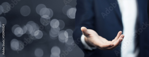Businessman in suit introduce something on dark background photo
