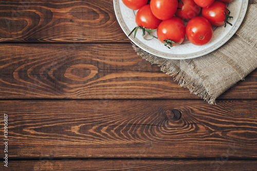 Fresh ripe tomatoes on a plate. Top view. Rustic wood background with copyspace