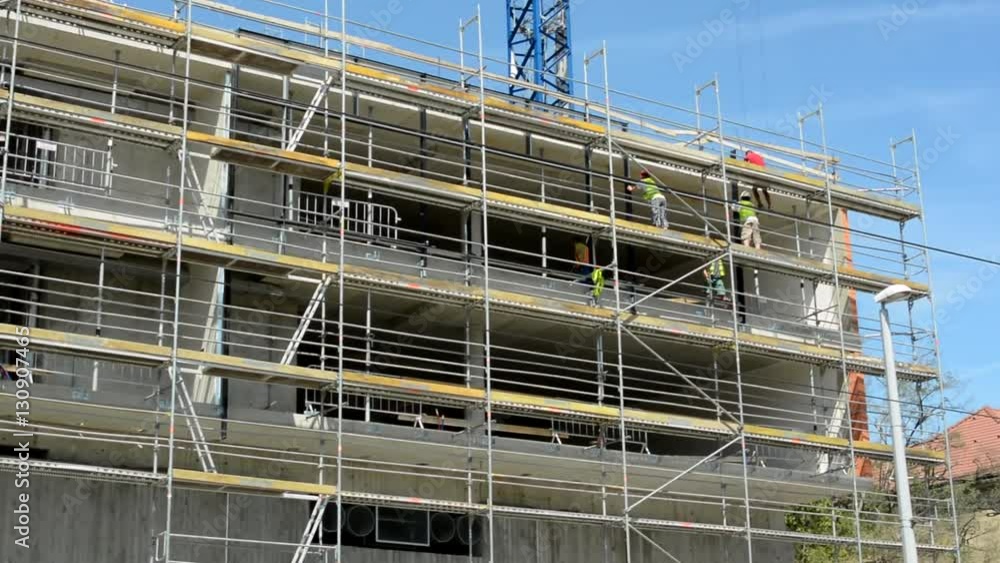 view of the large scaffolding by the building in the city - sunny day - blue sky view of the large scaffolding by the building in the city - sunny day - blue sky