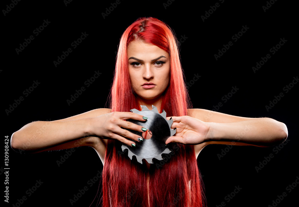 Portrait of beautiful girl with circular saw blade. Bretty naked woman, long red hair, nude body