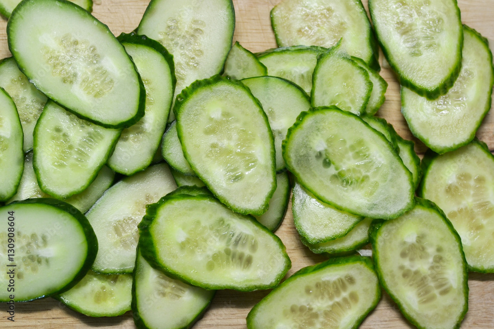 thin slices of cucumbers on a wooden table thin slices of cucumbers on a wooden table