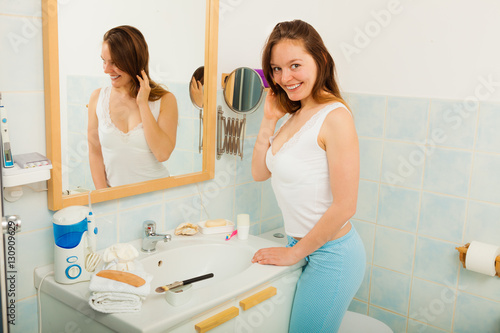 Woman without makeup in bathroom.