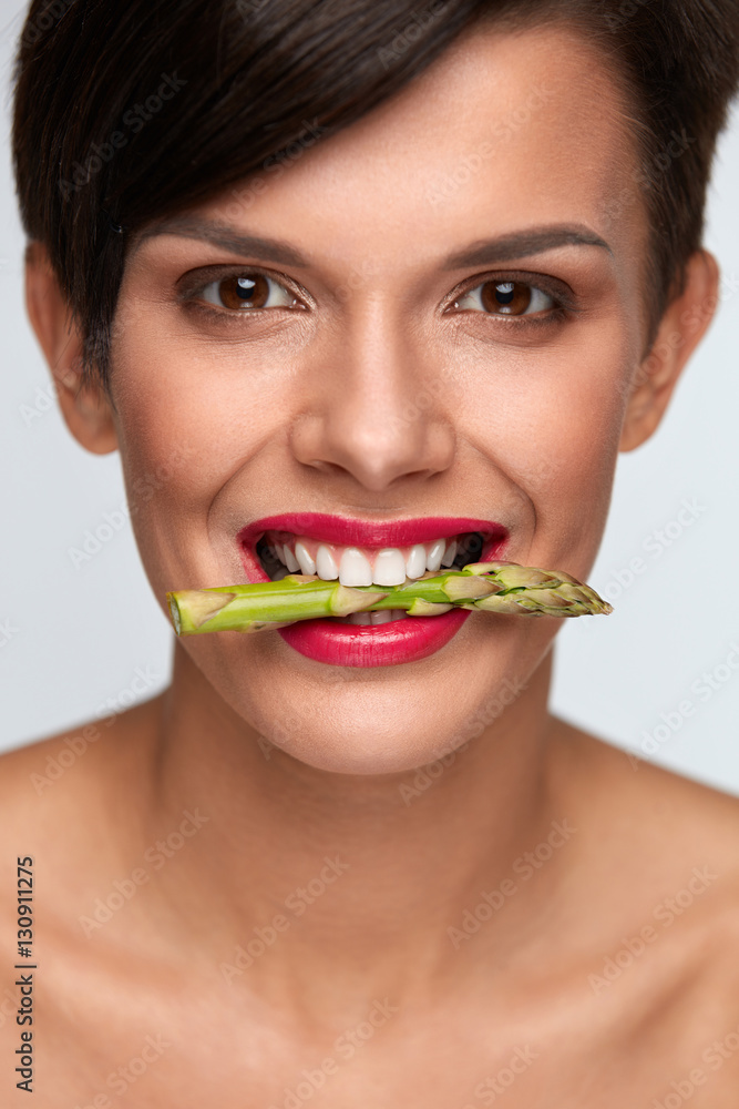 Healthy Eating. Beautiful Woman Holding Asparagus Between Teeth Healthy Eating. Beautiful Woman Holding Asparagus Between Teeth