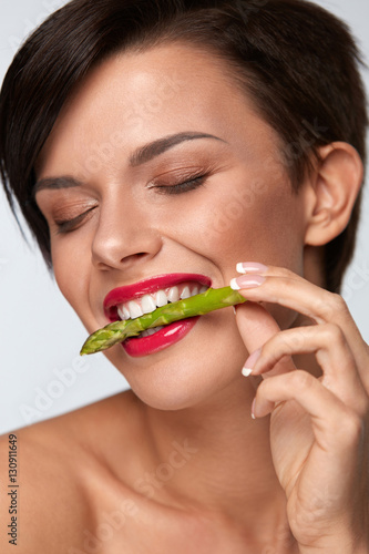 Healthy Foods. Beautiful Woman Eating Fresh Asparagus
