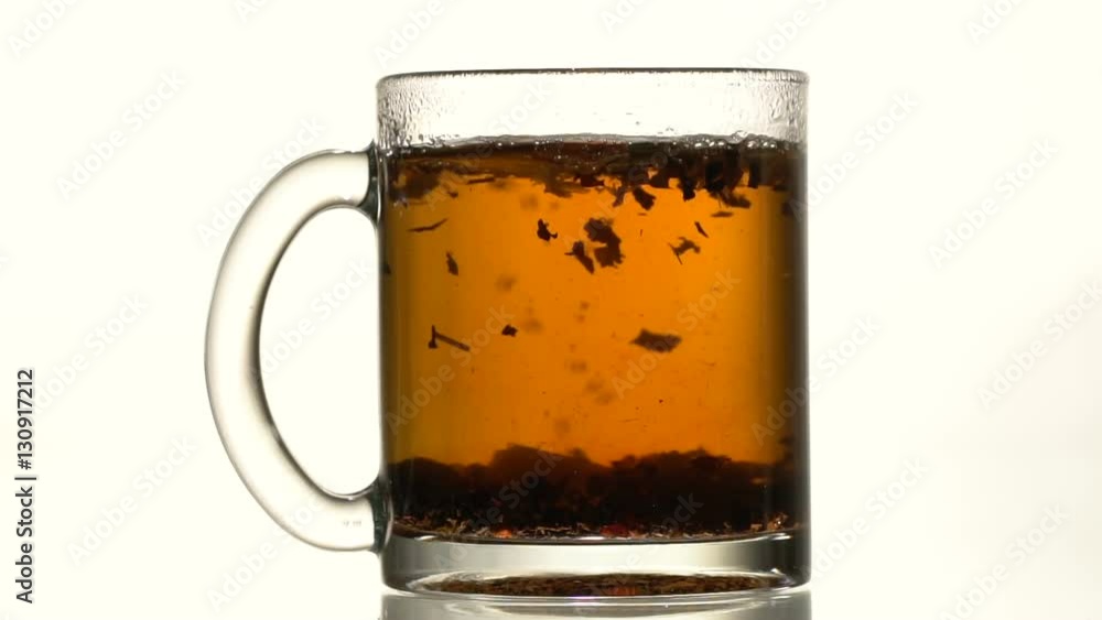 A glass cup of black tea throw refined sugar. Slow motion. Close-up A glass cup of black tea throw refined sugar. Slow motion. Close-up