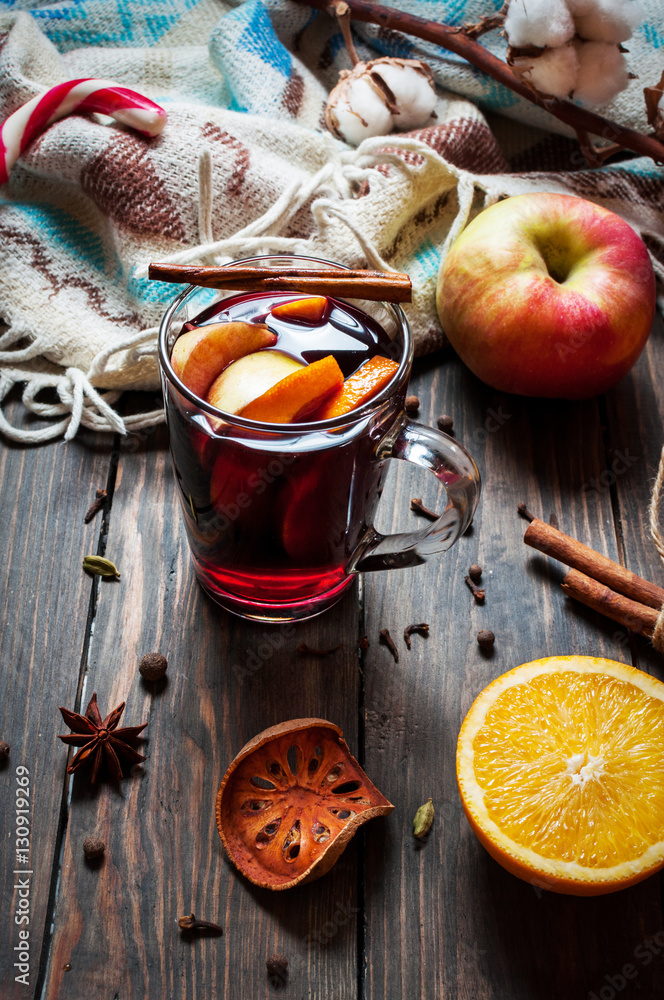 Hot mulled wine with spices, apple and orange on wood