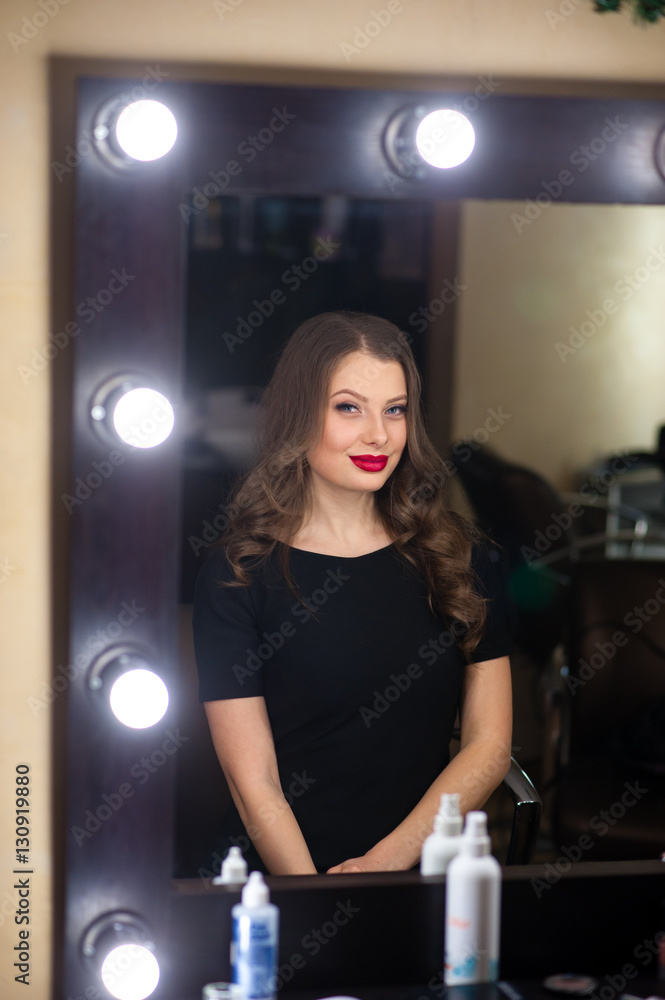 Beautiful girl does makeup and looks in the mirror