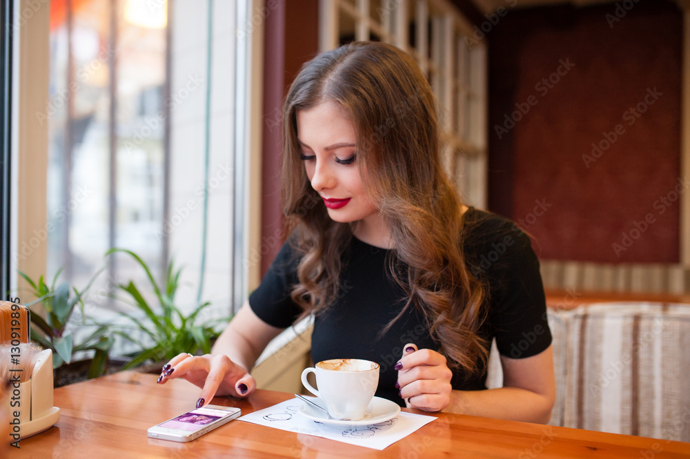 Beautiful girl drinking coffee and looking in the phone Beautiful girl drinking coffee and looking in the phone