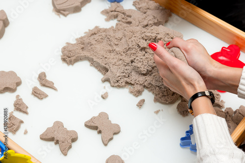 woman hands making a figure from wet sand