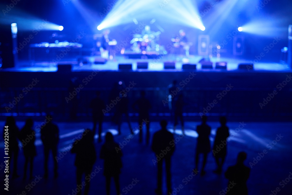 Blurred concept of night life. Crowd in front of stage with blue concert lights.