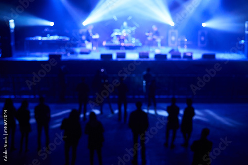 Blurred concept of night life. Crowd in front of stage with blue concert lights.