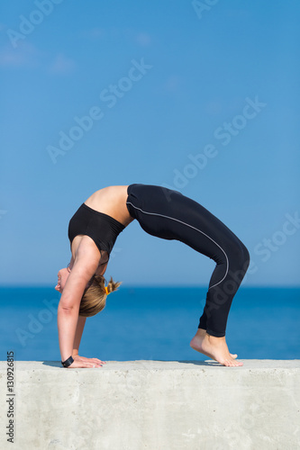 Young sportswoman doing exercises against the sea