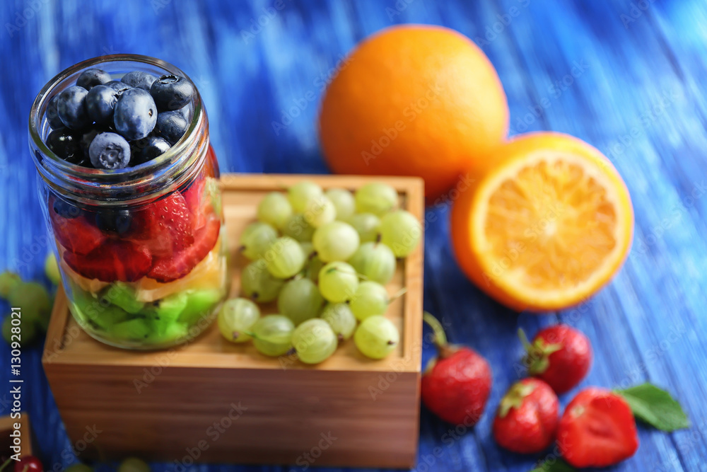 Glass jar with fruits and berries on wooden box Glass jar with fruits and berries on wooden box