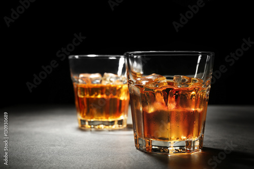 Glasses of whisky on grey textured table closeup