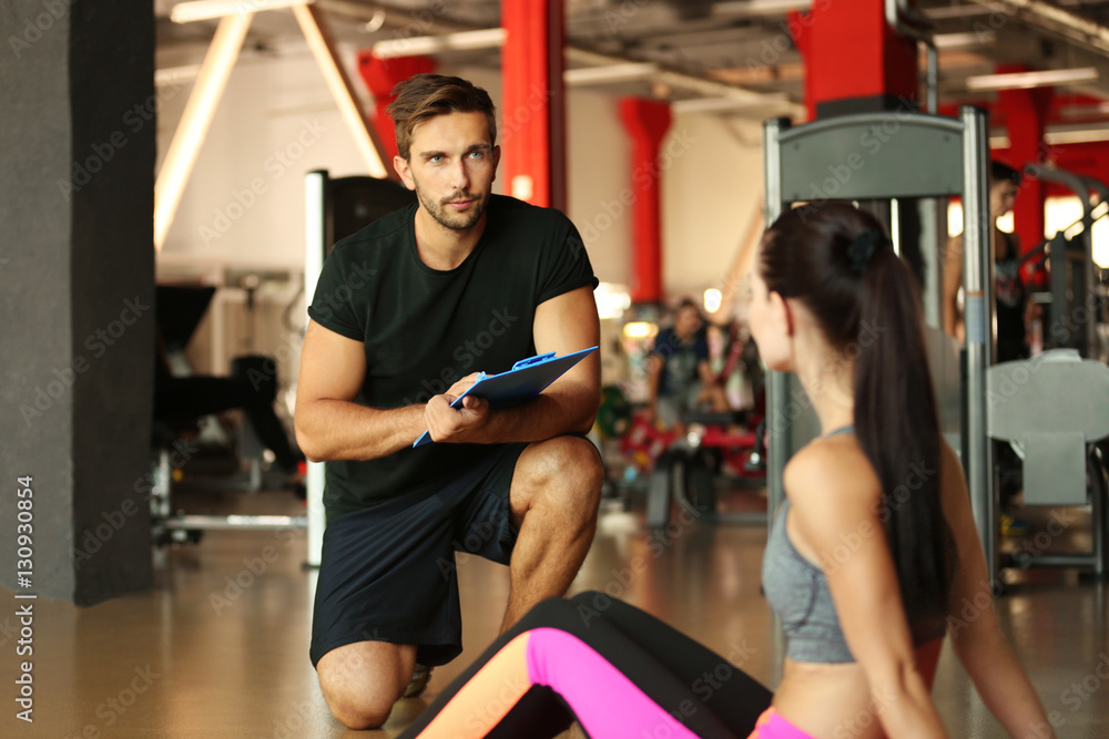 Young athletic woman doing exercises with trainer in gym Young athletic woman doing exercises with trainer in gym