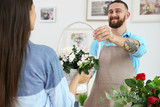 Handsome florist giving basket with flowers to customer