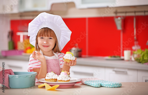 Little girl with cakes in kitchen