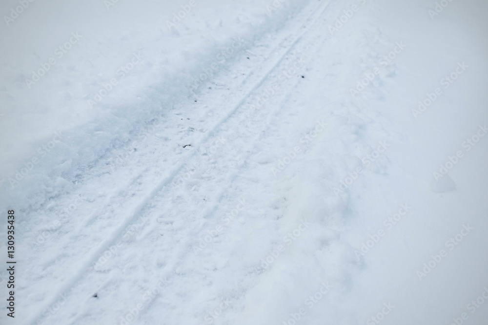Snowy tire tracks on the winter road. Car tracks on snow city street. 