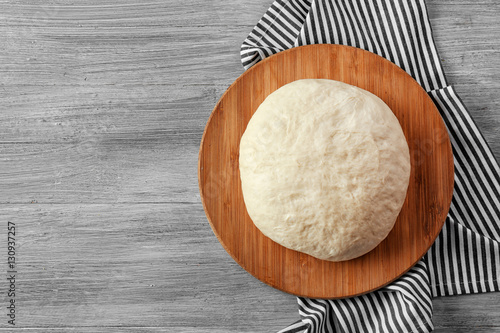 Wooden board with raw dough on kitchen table