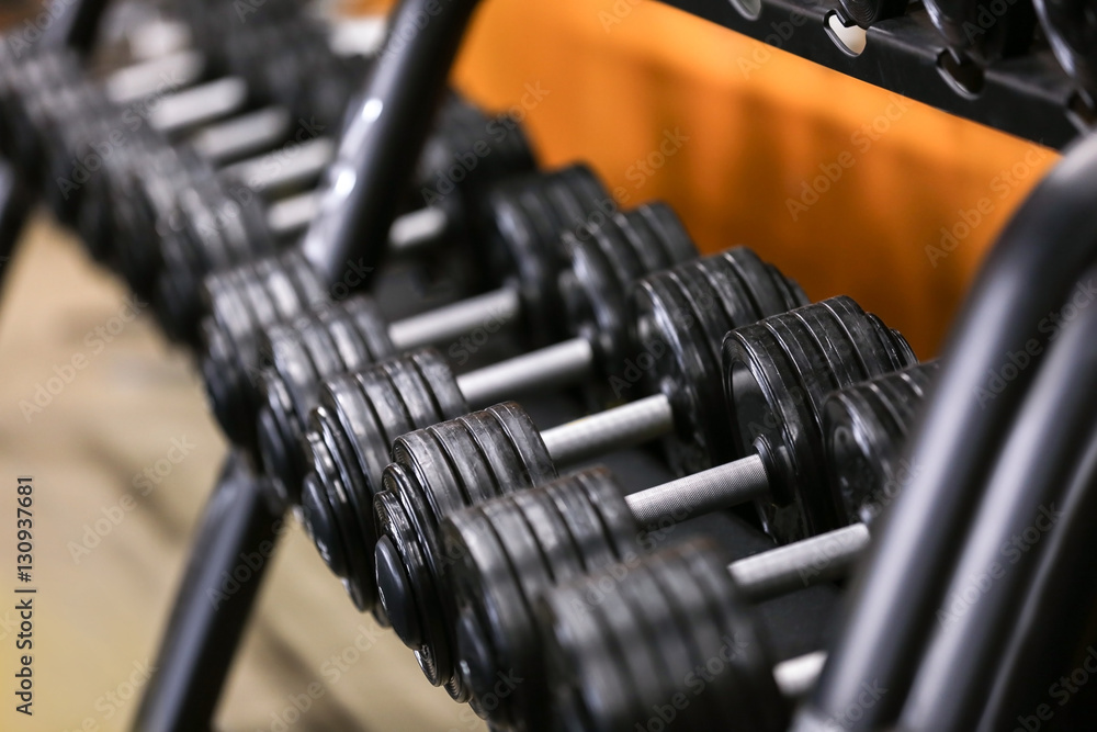 Rack with different dumbbells in gym, close up Rack with different dumbbells in gym, close up