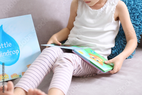 Funny little girl reading b...