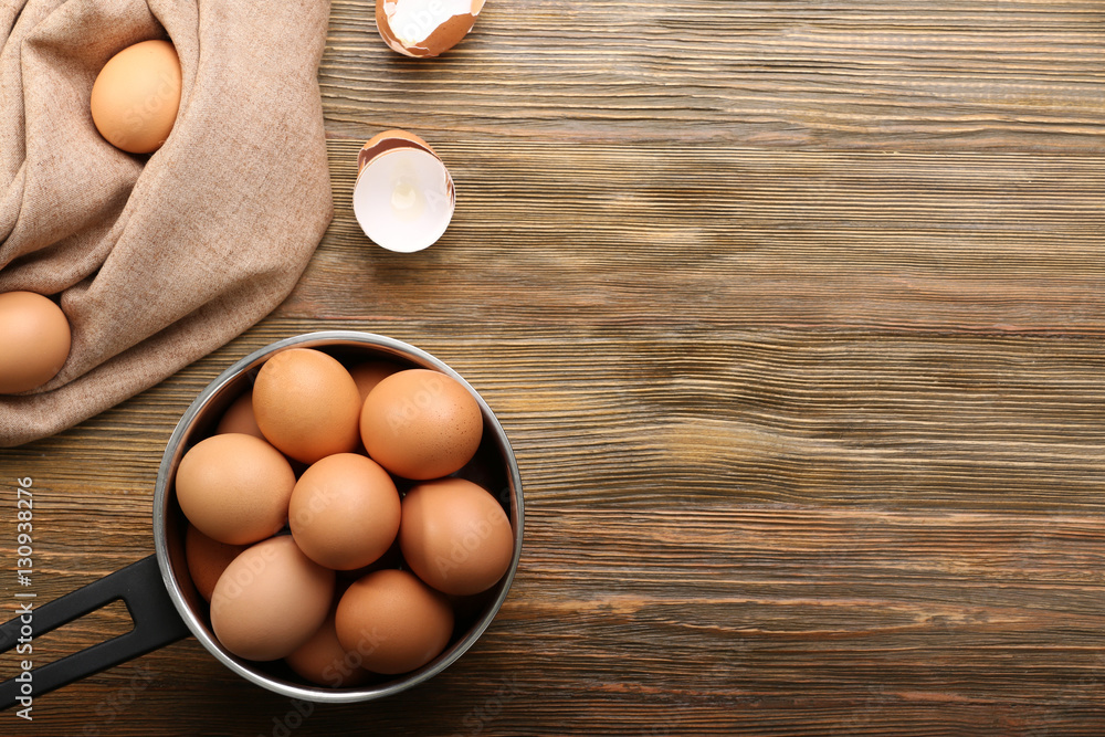 Raw eggs in saucepan on wooden table Raw eggs in saucepan on wooden table