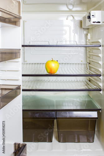 A yellow apple on a shelf in a refrigerator