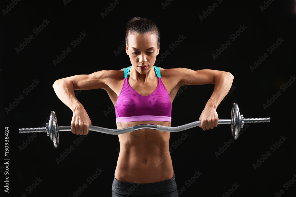 Sporty young woman with barbell on black background Sporty young woman with barbell on black background
