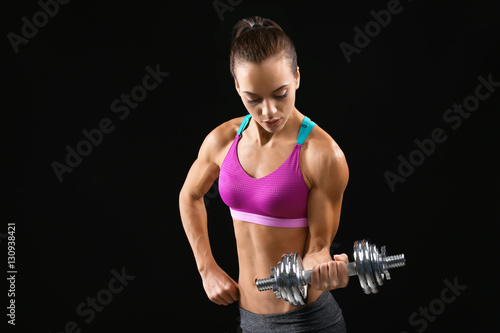 Sporty young woman with dumbbell on black background © Africa Studio