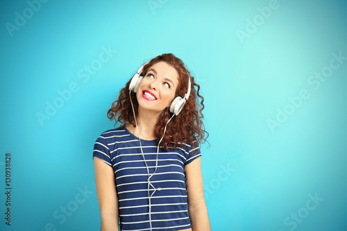 Portrait of expressive young model in striped suit with earphones on blue background