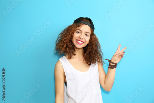 Portrait of expressive young model in white shirt with cap on blue background