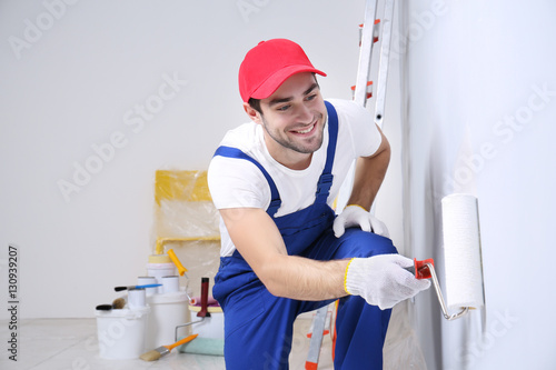 Young worker painting wall ...