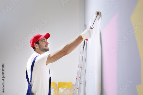 Young worker painting wall ...
