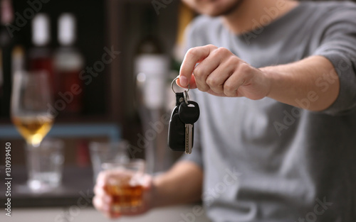 Close up view of man with car key and alcoholic beverage. Don't drink and drive concept