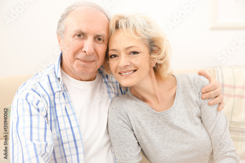 Happy senior couple sitting on sofa at home