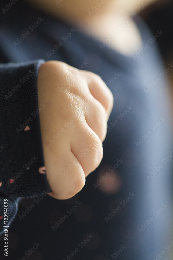 Small white baby fist close up on a blue girl dress