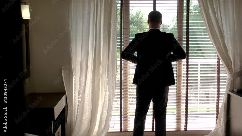 Man in suit near window. Groom putting on his jacket. I've been waiting for this. Day of wedding ceremony. Man in suit near window. Groom putting on his jacket. I've been waiting for this. Day of wedding ceremony.