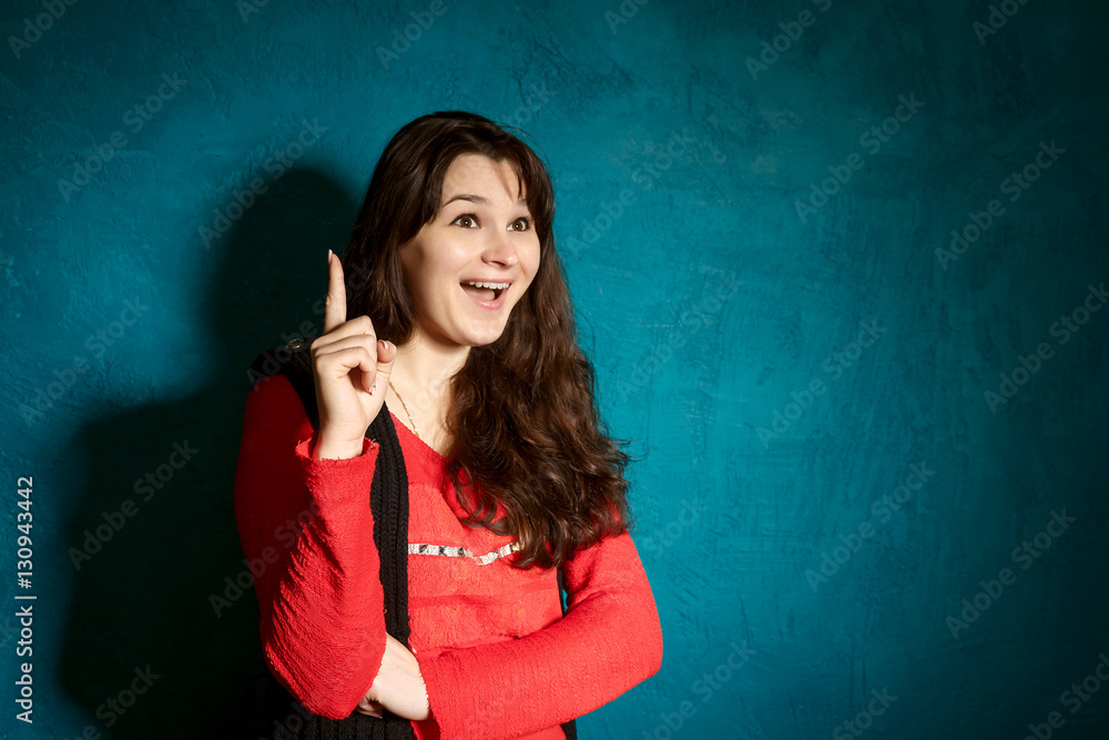 young brunette woman in a beauty blouse and black jacket standing against the backdrop of a blue wall young brunette woman in a beauty blouse and black jacket standing against the backdrop of a blue wall
