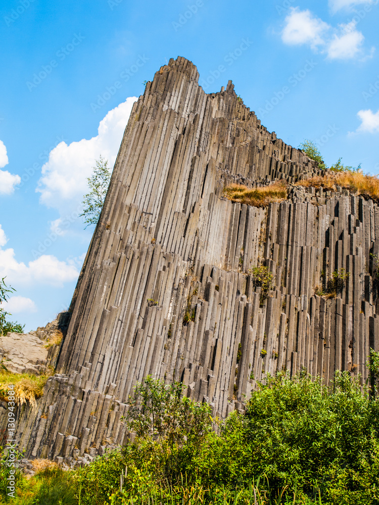 Unique basalt organ pipes rock formation of Panska skala near Kamenicky Senov in Northern Bohemia, Czech Republic, Europe. Shot on sunny summer day with blue sky and white clouds.