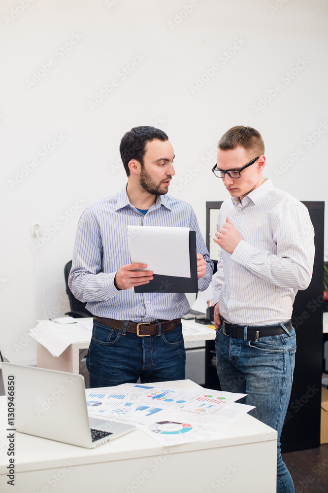 Two cheerful webdesigners standing at office Two cheerful webdesigners standing at office