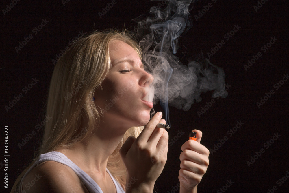 Fototapeta premium blond young woman smoking on black background