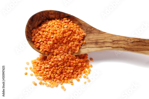 red lentils in wooden spoon isolated on white